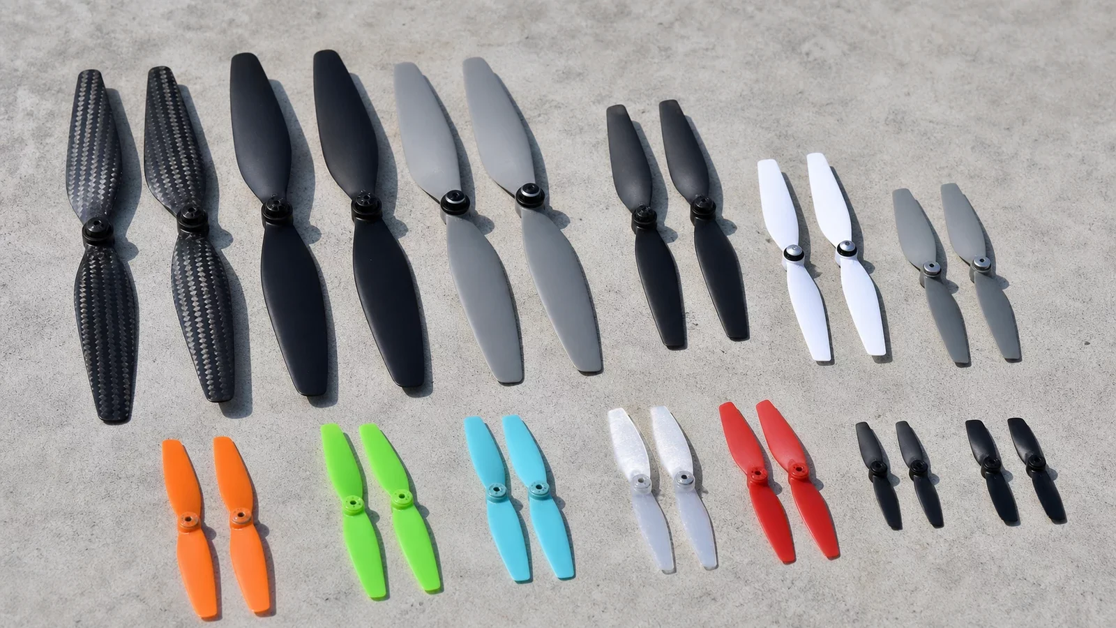 Assortiment d'hélices de drone de tailles et couleurs différentes sur fond neutre