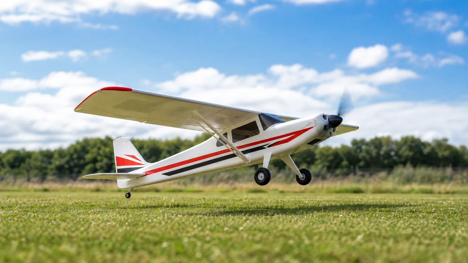 Avion télécommandé au décollage sur une piste herbeuse, ciel bleu
