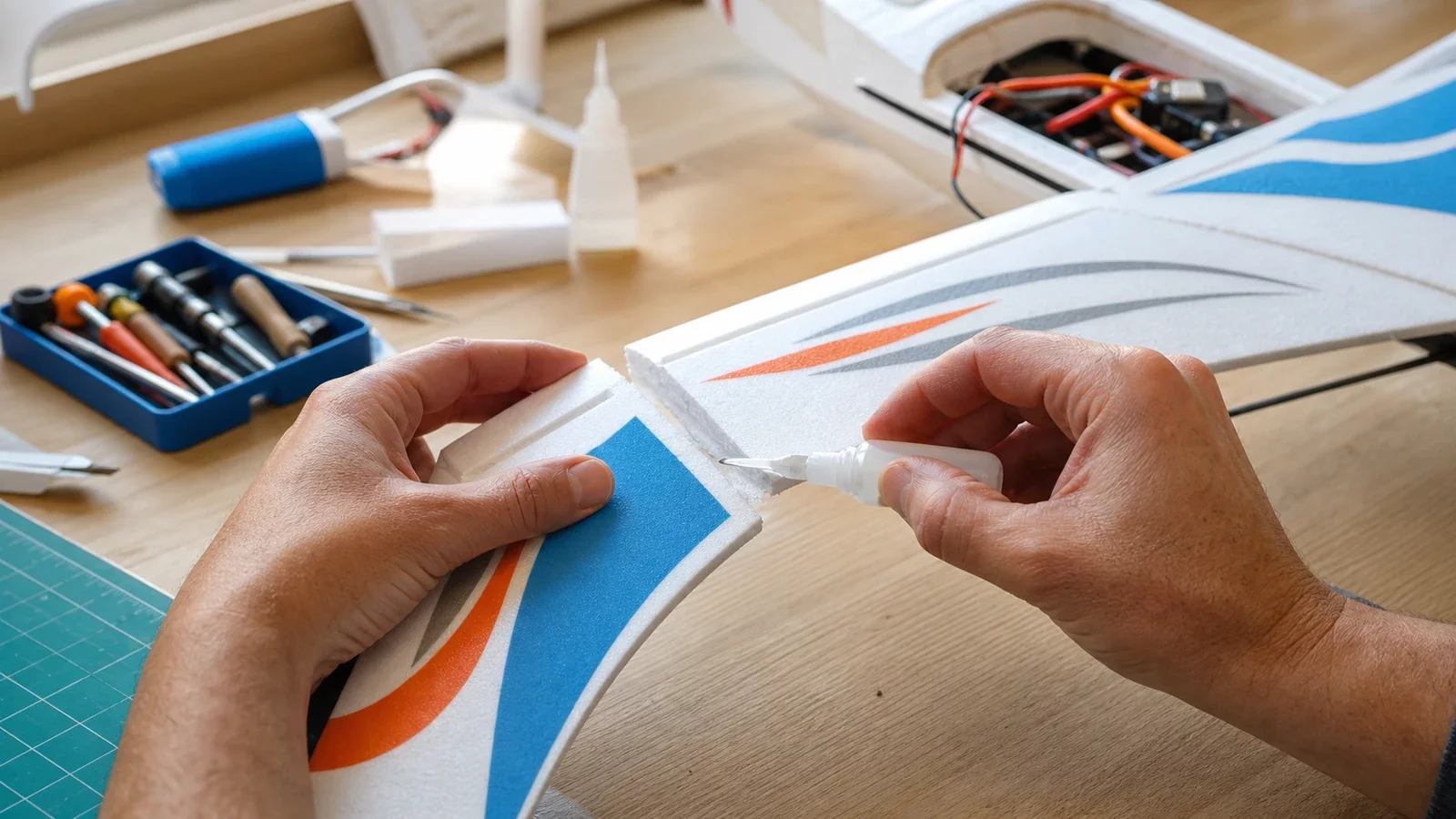 Mains réparant l'aile en mousse d'un avion télécommandé avec de la colle